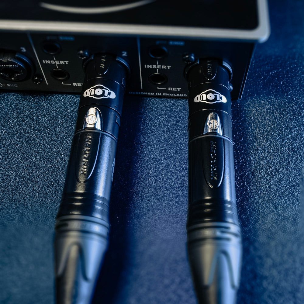 Two Cloudlifter guitar cables plugged into an audio interface on a blue surface.