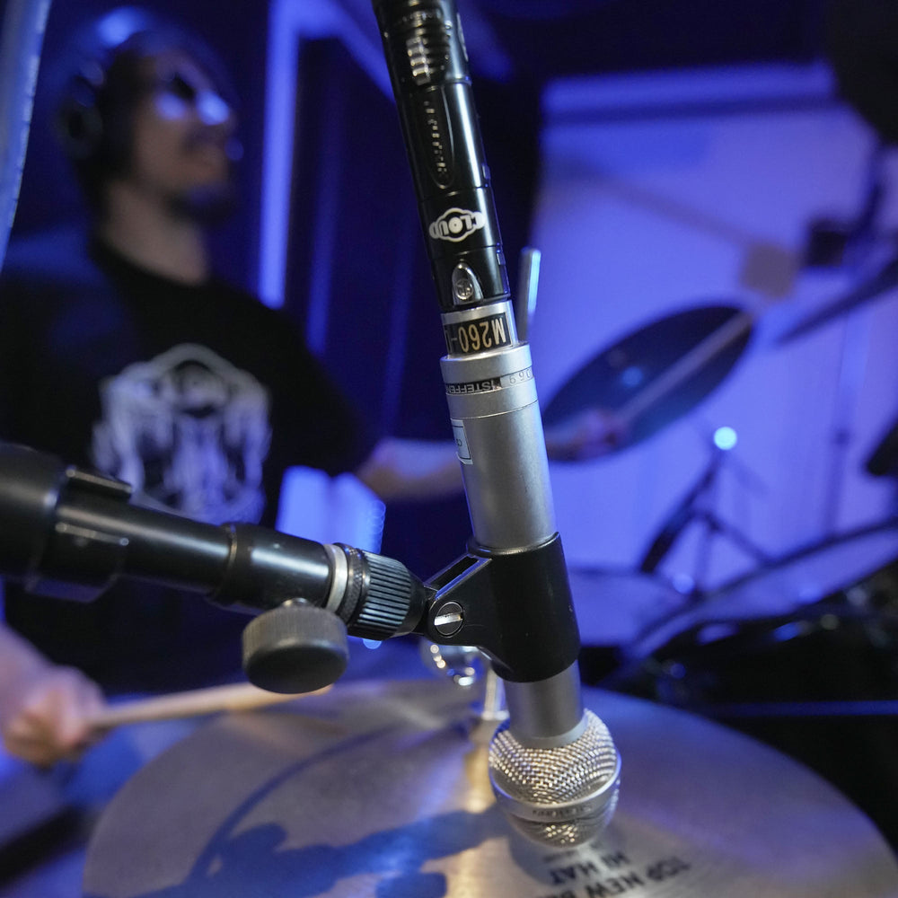 Close-up of a cloudlifter on a drum with a person playing drums in the background.